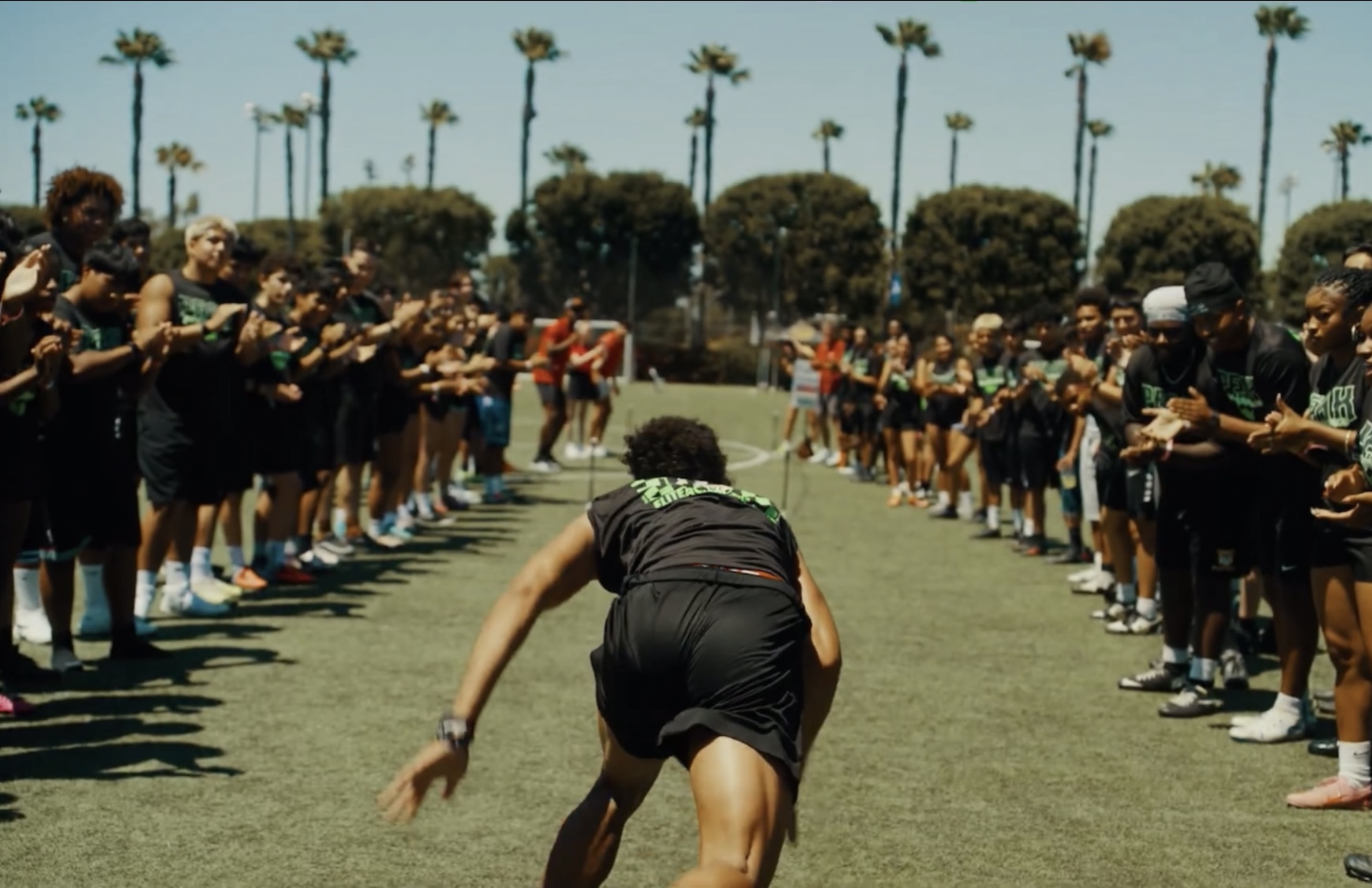 Athlete beginning a field sprint test between two lines of cheering young athletes