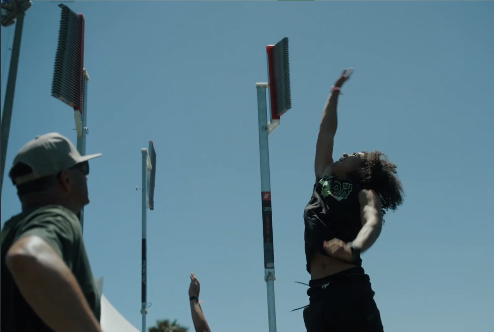 Athlete reaching up during a measured vertical jump test on an outdoor field